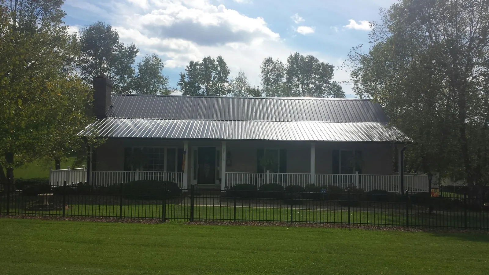 Gray metal roof on a brick ranch with a full width front porch — Gutter Guard Installation work by our crew in Marble Hill