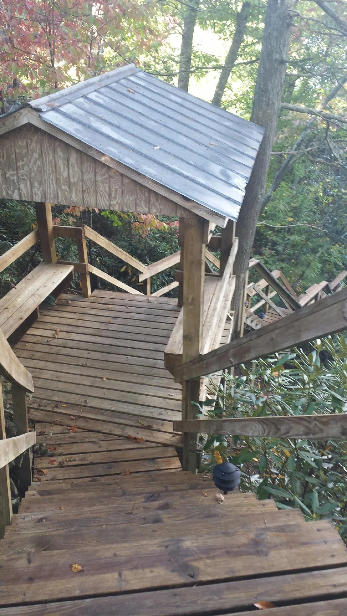 Metal roofed shelter over wooden steps on a wooded walkway — Skylight Repair & Installation work by our crew in Marble Hill