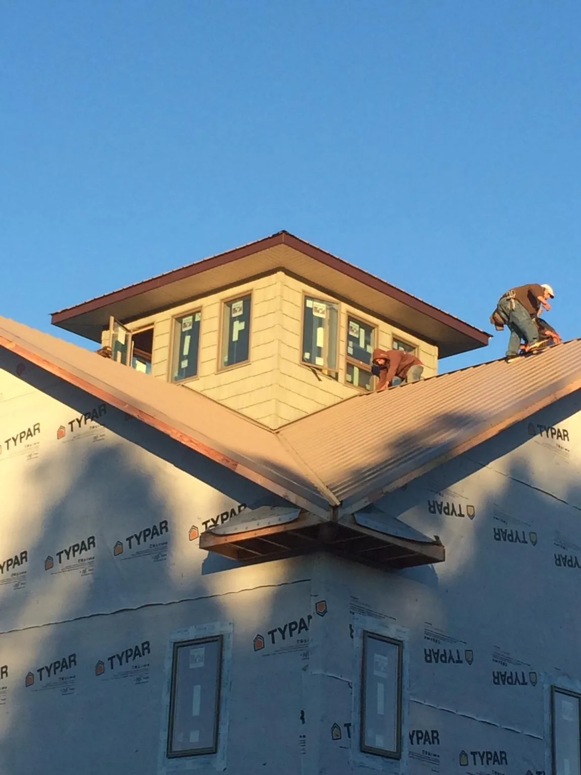 Roofers working around a rooftop cupola on a new metal roof at sunset — Roof Waterproofing in Marble Hill by Roofing Brothers